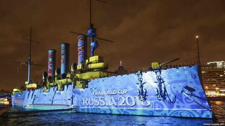 На крэйсэры «Аўрора» ў Санкт-Пецярбургу, які даў сыгнал да перавароту ў 1917 годзе, сьвятлом малююць лягатып чэмпіянату сьвету па футболе 2018 году (фота 4 лістапада 2017 году)
